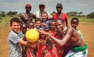 A child poses for a photo with a group of locals while on vacation.