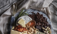 A spread of cheese, chocolate, fruit and nuts.