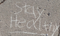 "Stay Healthy" written in chalk on a sidewalk.