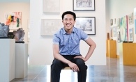 Vincent Cao, a member of the 2019 Senior Spotlight, sits in front of a wall of art.