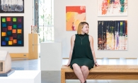 Grace Hanson, part of the 2019 Senior Spotlight, poses in front of a wall of paintings.