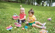 Two babies wearing RubyScootz play on a lawn.