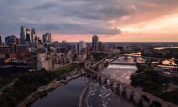 A shot of the Minneapolis skyline at sunset, with the Stone Arch Bridge in the foreground.