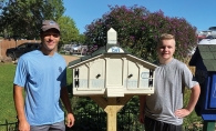 Bryce Alexander posing with one of his Little Free Libraries.