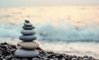 A stack of balanced rocks on a shoreline, a metaphor for achieving a balanced life.