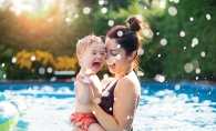 A woman holds a child in a pool.