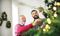 Two men decorate a Christmas tree