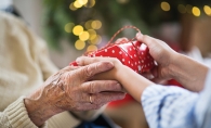 Someone hands a senior a gift from the Be a Santa to a Senior program.