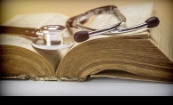 An old stethoscope sits on an old medicine book.