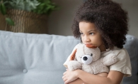 A stressed child holds a teddy bear.