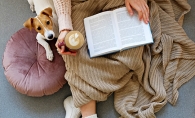 Woman reading while snuggled with dog
