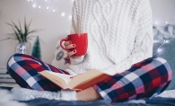 Woman reading and drinking from a red mug.