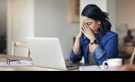 A woman sitting at a computer holds her head in her hands after making a mistake.