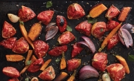 Roasted tomatoes, carrots and onions in a sheet pan.