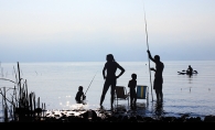 A family fishes on a lake while on vacation.