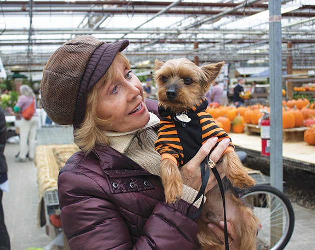 A woman holds a dog at Tonkadale Greenhouse's Biscuits & Blooms event.