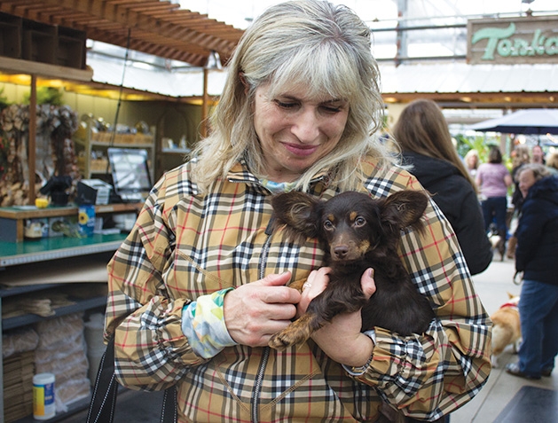 A woman holds her dog at Tonkadale Greenhouse's Biscuits & Blooms event.