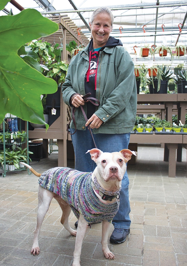 A woman holds her dog on a leash at Tonkadale Greenhouse's Biscuits & Blooms event.