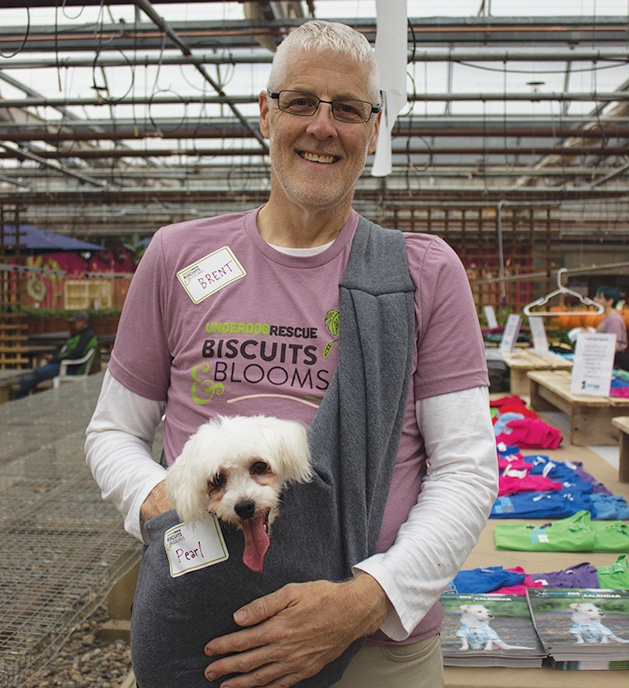 A man holds his dog at Tonkadale Greenhouse's Biscuits & Blooms event