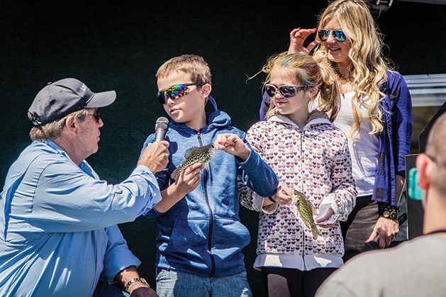 A boy and girl hold up their catches while being interviewed at the 51st Annual Minnesota Bound Crappie Contest