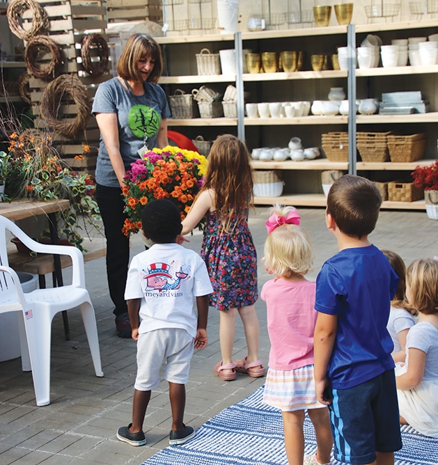 A woman hands out flowers to children at Tonkadale Greenhouse's Third Thursdays event.