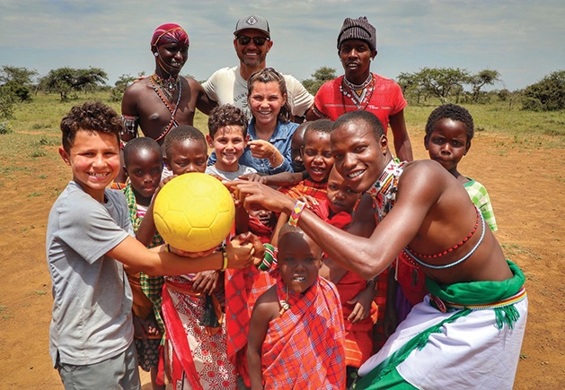 A child poses for a photo with a group of locals while on vacation.