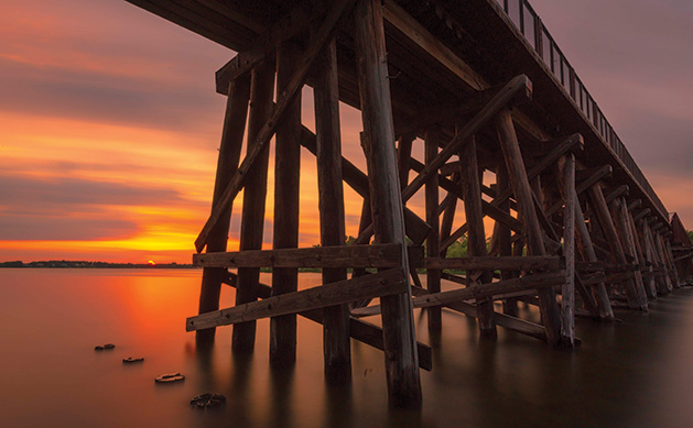 A long exposure photograph shows a summer sunset on Lake Minnetonka