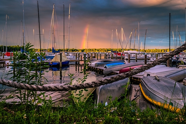 Rainbows paint the sky over boats on Lake Minnetonka.