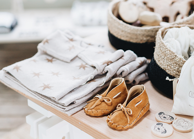 Children's clothing, including shirts and shoes, sits on a table.