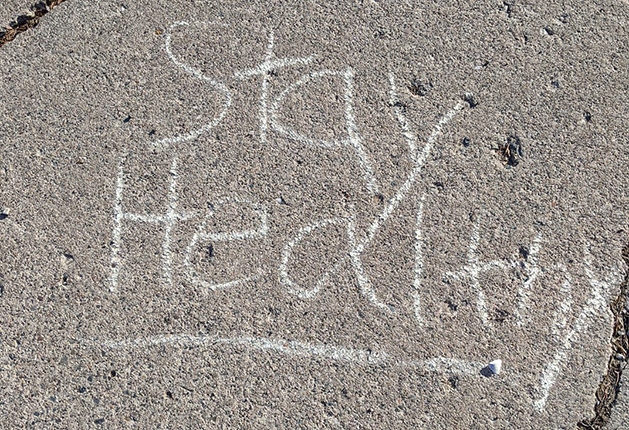 "Stay Healthy" written in chalk on a sidewalk.