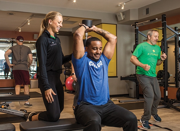 A personal trainer helps a man work out at Fitspace Wayzata, a no membership model fitness club.