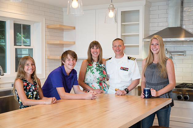 A military family poses for a photo in their kitchen.