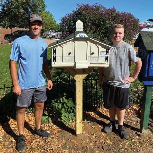 Bryce Alexander posing with one of his Little Free Libraries.