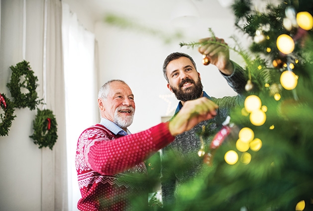 Two men decorate a Christmas tree