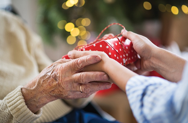 Someone hands a senior a gift from the Be a Santa to a Senior program.