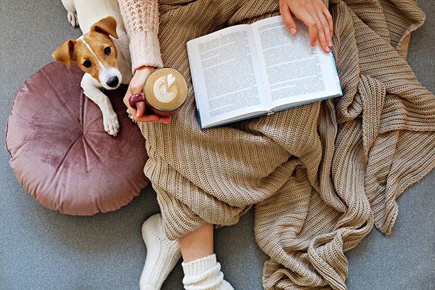 Woman reading while snuggled with dog