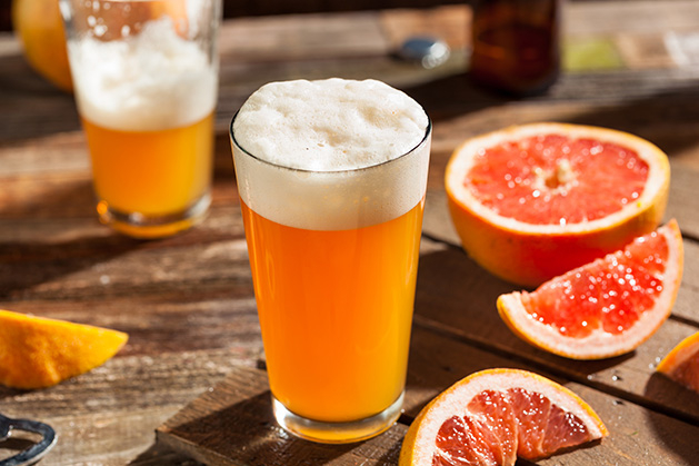 A local summer beer sits on a patio table next to a grapefruit.