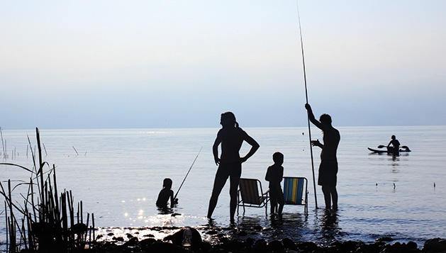 A family fishes on a lake while on vacation.