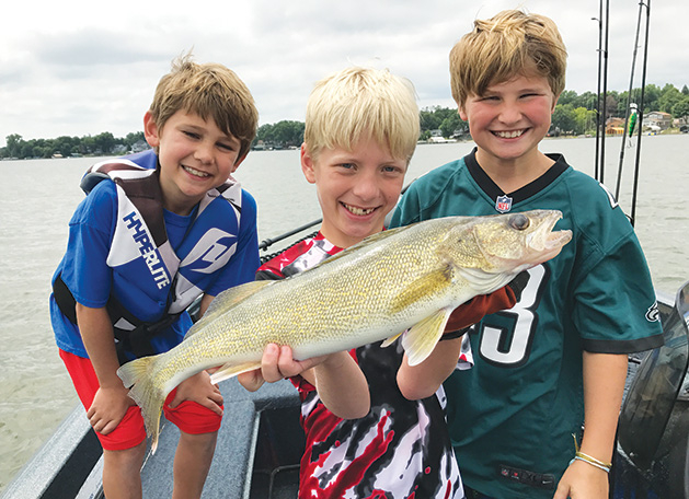 Three boys hold a walleye they caught from Lake Minnetonka, thanks to the help of the Westonka Walleye Program.