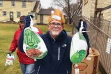 An ICA Food Shelf volunteer holds up two turkeys for Thanksgiving dinner.