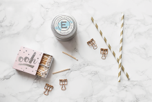 Matches, an Excelsior Candle Co. candle and two gold and white straws.