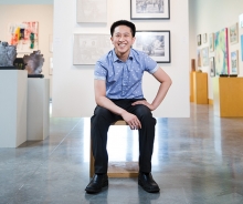 Vincent Cao, a member of the 2019 Senior Spotlight, sits in front of a wall of art.