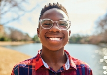 A child smiles, wearing their new glasses after a Vistagraph reading comprehension test.