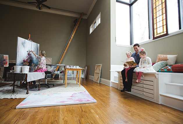 Jillian Lee paints while her husband reads to their children