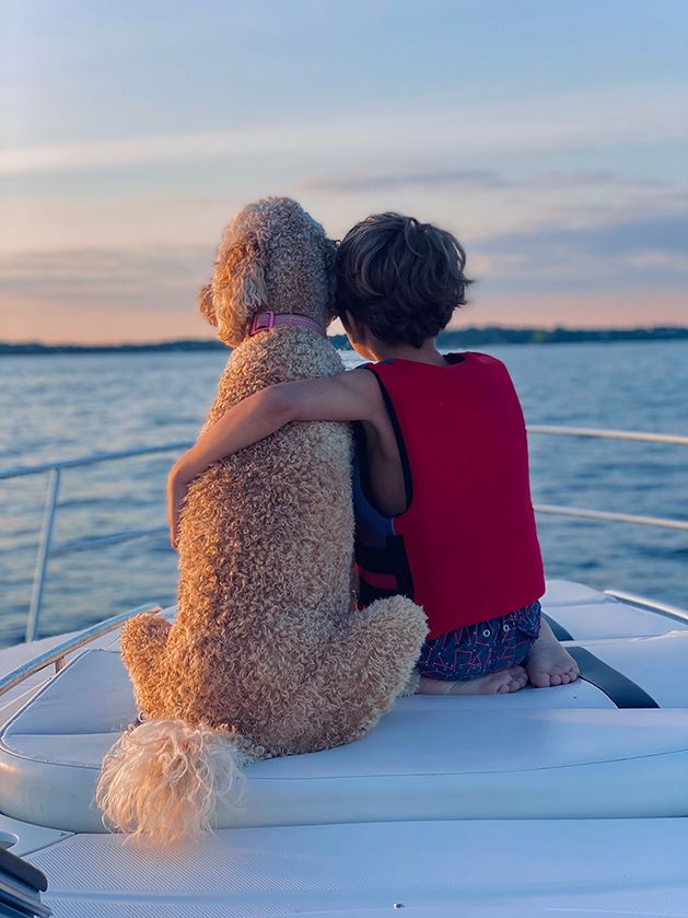 A boy sits with his dog on a boat on Lake Minnetonka