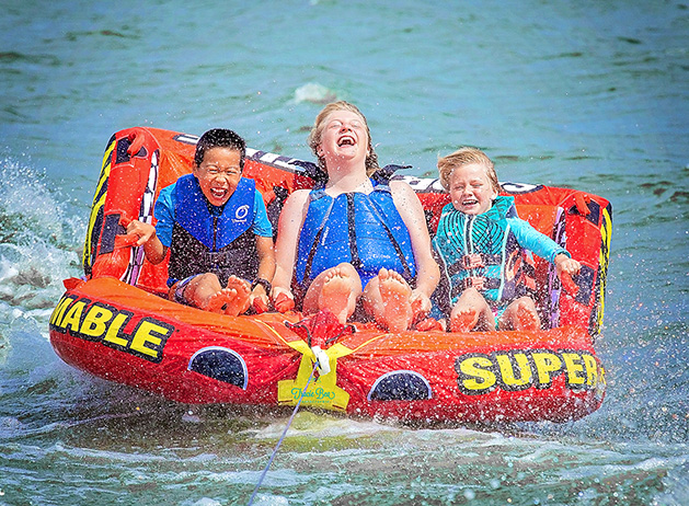 Three children laugh while tubing on Lake Minnetonka.